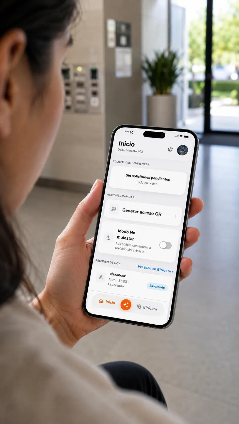 Residente en el lobby del edificio revisando la pantalla de inicio de la app LUMA: solicitudes pendientes, generar acceso QR, modo No molestar y el resumen del día